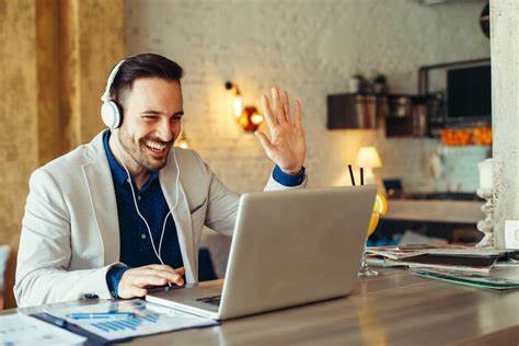 A man is waving to a person in an online meeting.
