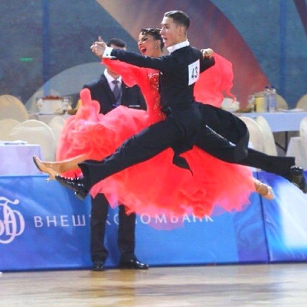A professional ballroom couple doing the Quickstep and leaping in midair across the floor.