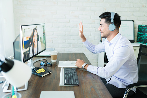 A man waving to a client on an internet conference call.